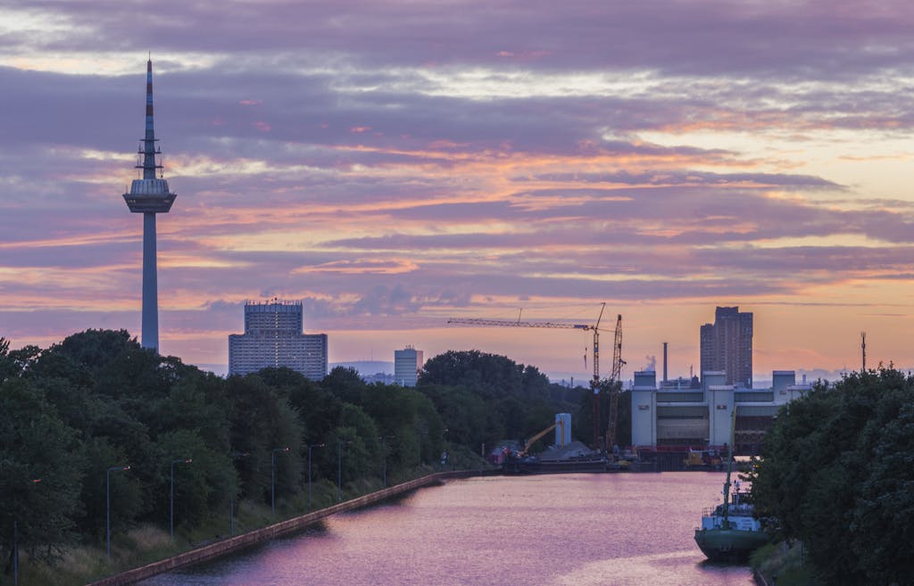 Colorful sunset over Mannheim skyline featuring the iconic Fernmeldeturm tower and urban landscape.