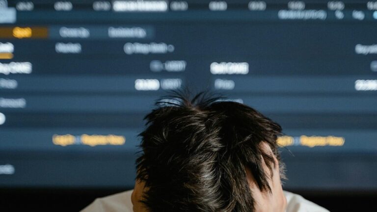 Businessman in white shirt stressed with declining stock prices on the screen.